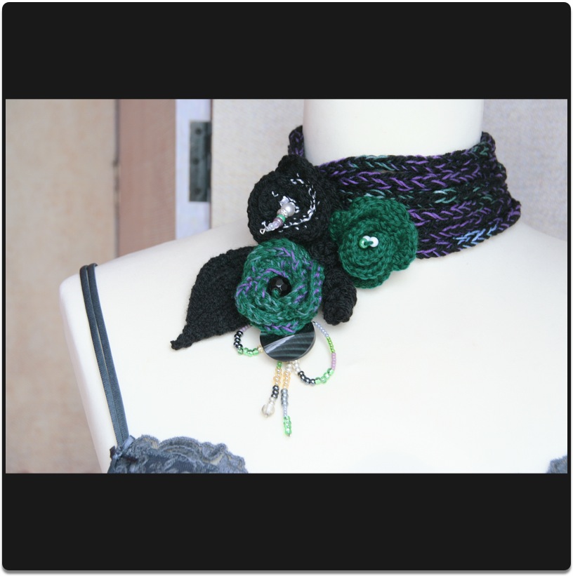 Halschmuck mit Blumenanstecker gestrickt Schwarz-Gr&uuml;n-Violett